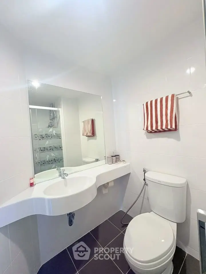 Modern bathroom with sleek white fixtures and large mirror in a contemporary home.