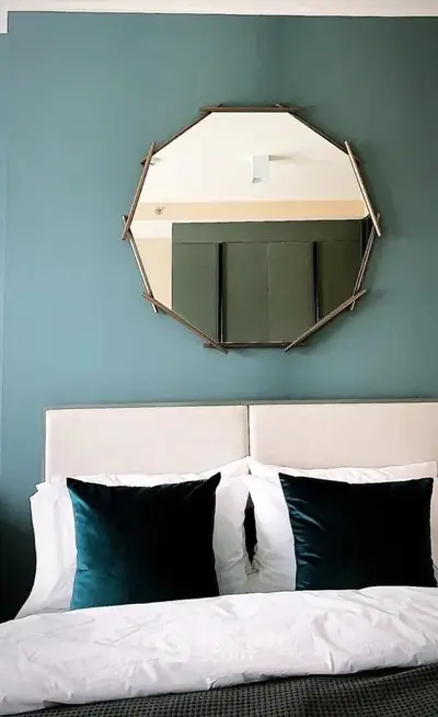 Elegant bedroom with stylish mirror and plush pillows, perfect for modern living.
