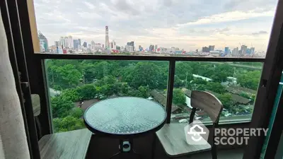 Stunning city view from a high-rise balcony with cozy seating area.