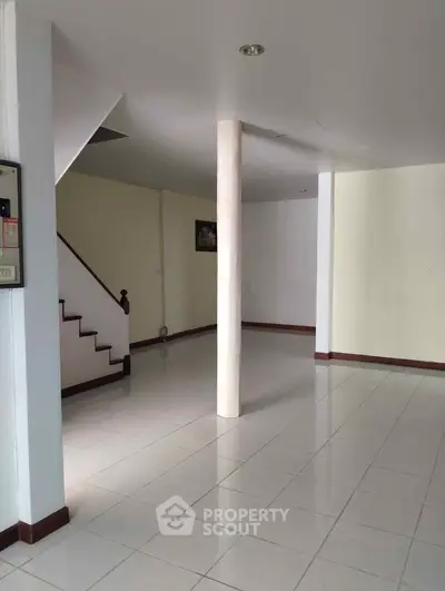Spacious open-plan living area with tiled flooring and staircase, ideal for modern living.
