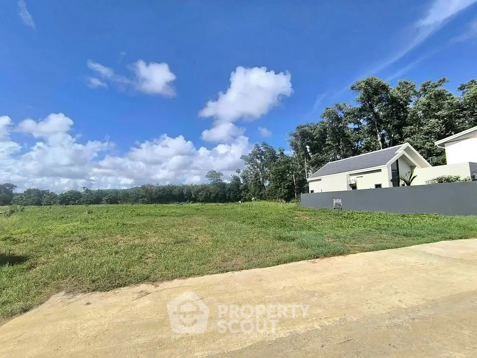 Spacious vacant land with lush greenery and clear blue sky, perfect for building your dream home.