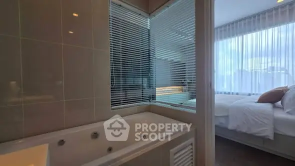 Modern bathroom with bathtub and view into a cozy bedroom