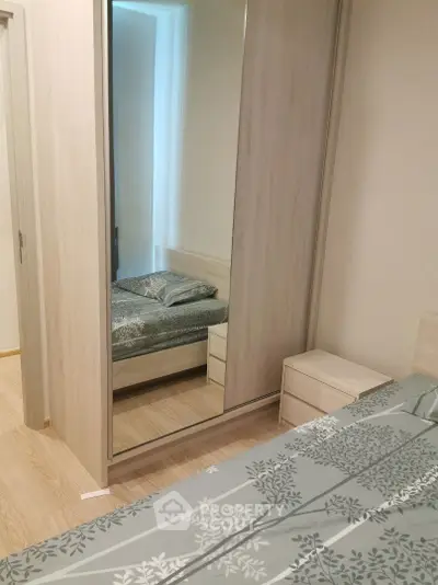 Modern bedroom with mirrored wardrobe and stylish bedding in a cozy apartment.