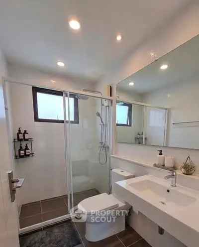 Modern bathroom with glass shower, large mirror, and sleek fixtures