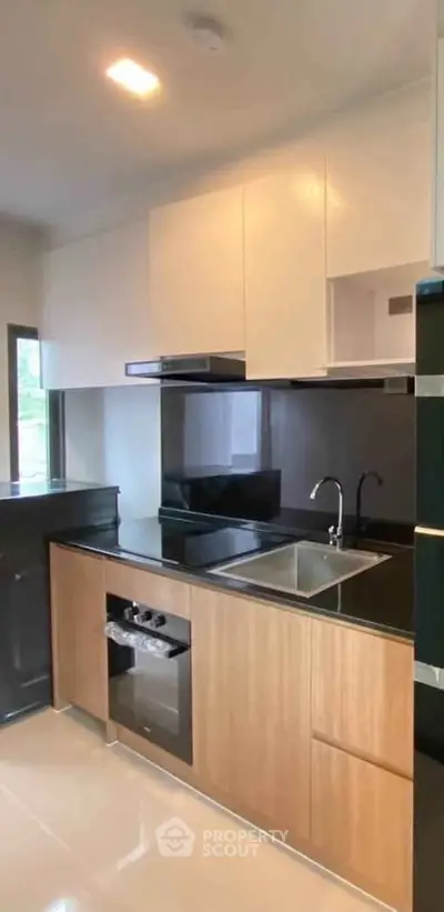 Modern kitchen with sleek cabinetry and built-in oven in a stylish apartment.