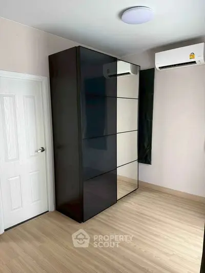 Modern bedroom with sleek black wardrobe and air conditioning unit