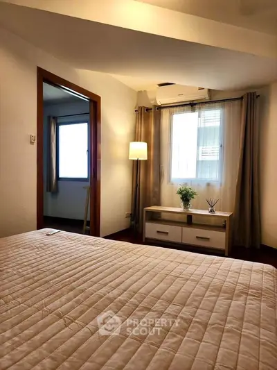 Cozy bedroom with natural light, modern decor, and air conditioning, perfect for relaxation.