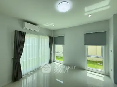 Bright and airy living room with large windows and modern air conditioning unit.