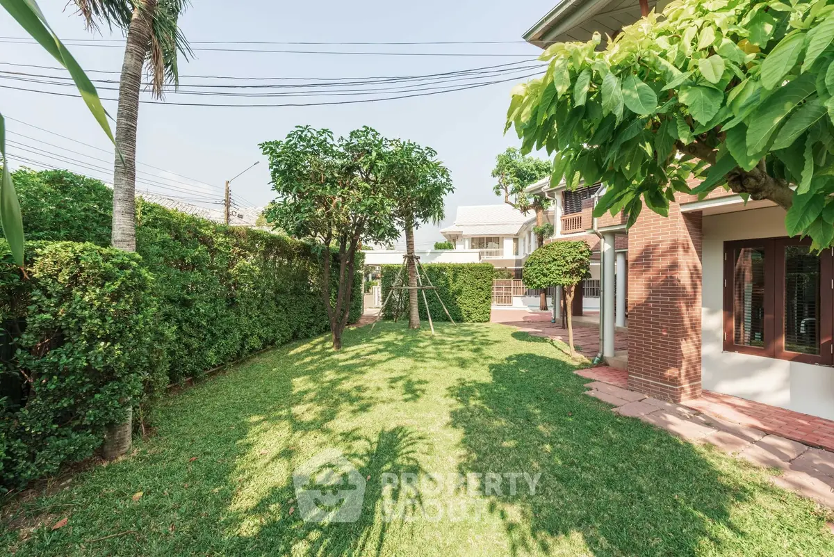 Spacious backyard with lush greenery and brick exterior in a serene residential area.