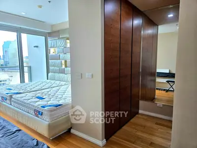 Spacious bedroom with large windows and city view, featuring a comfortable bed and ample closet space.