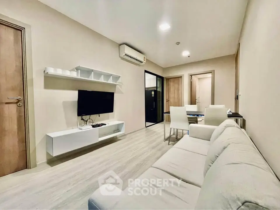Modern living room with sleek furniture and wall-mounted TV in a cozy apartment.