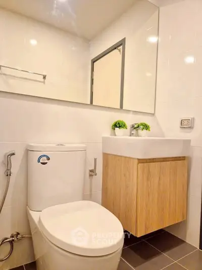 Modern bathroom with sleek fixtures and minimalist design, featuring a wall-mounted sink and large mirror.