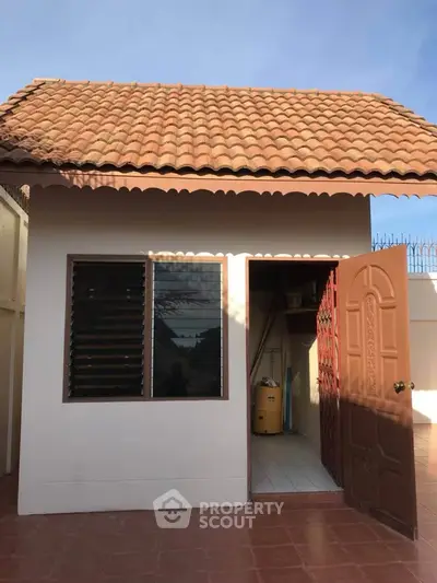 Charming small building with tiled roof and open door, perfect for storage or a cozy retreat.