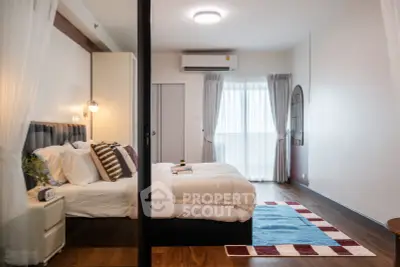 Modern bedroom with stylish decor, featuring a cozy bed, elegant lighting, and a large window for natural light.