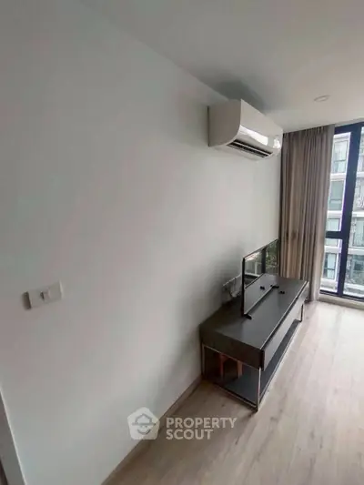 Modern living room with air conditioning and TV stand, featuring large window for natural light.