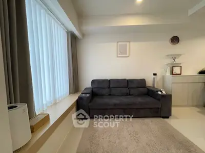 Modern living room with sleek gray sofa and large window, offering a cozy and inviting atmosphere.