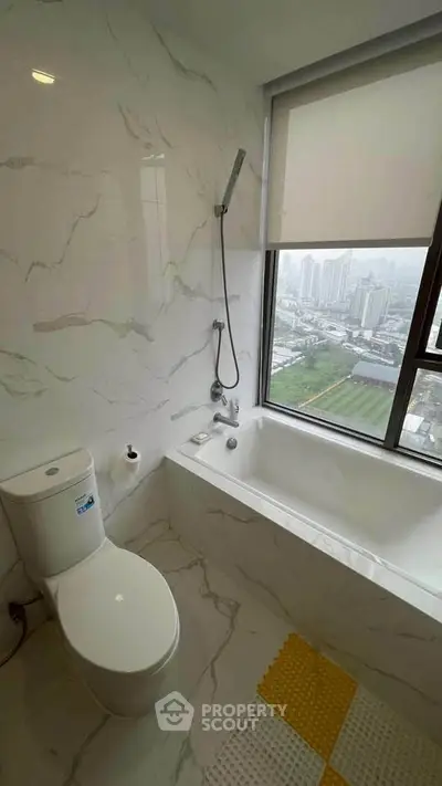 Modern bathroom with city view, featuring a sleek bathtub and elegant marble tiles.
