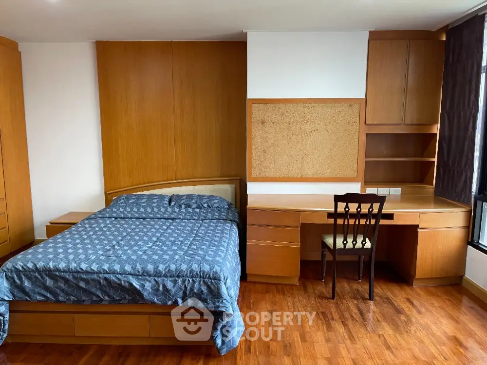 Spacious bedroom with wooden furniture and large window for natural light