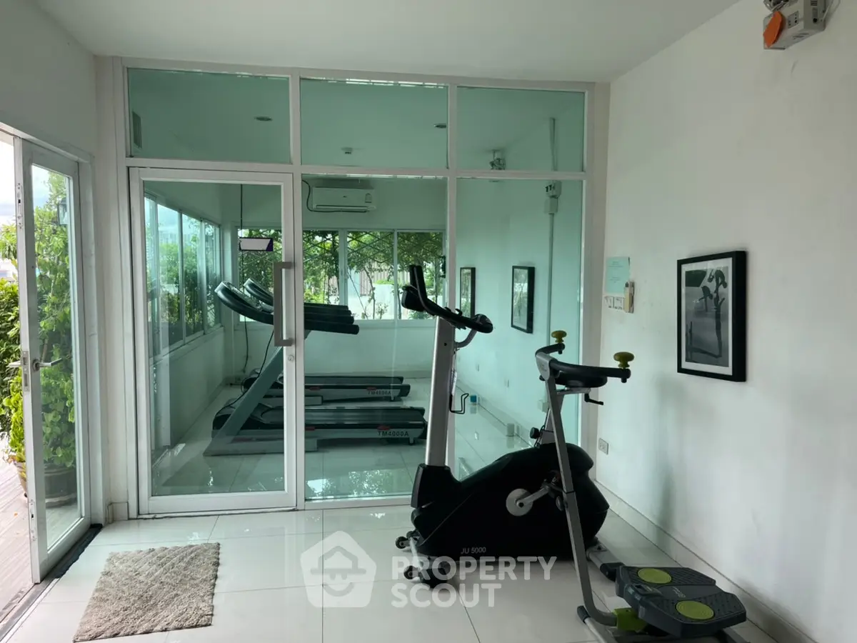 Modern gym with exercise equipment and glass walls in a residential building.