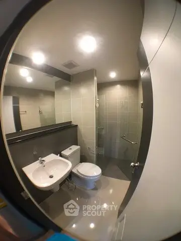 Modern bathroom with sleek fixtures and glass shower enclosure in contemporary apartment.