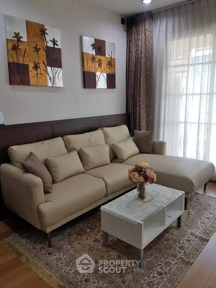 Elegant living room with beige sofa, stylish decor, and natural light from large windows.