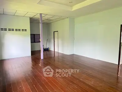 Spacious empty room with wooden flooring and white walls, ideal for customization.