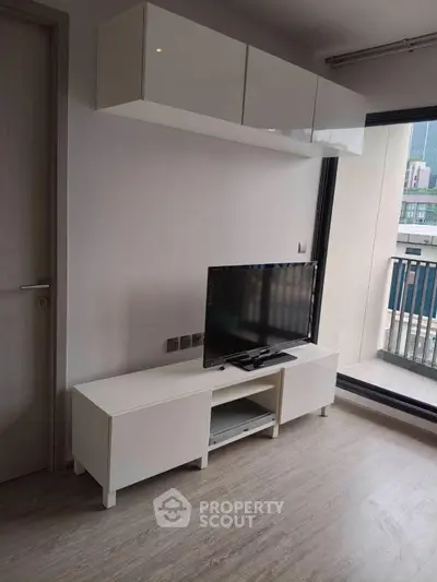 Modern living room with sleek TV stand and balcony view in urban apartment