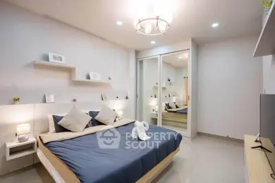 Modern bedroom with elegant decor and mirrored closet doors, featuring cozy lighting and stylish furnishings.