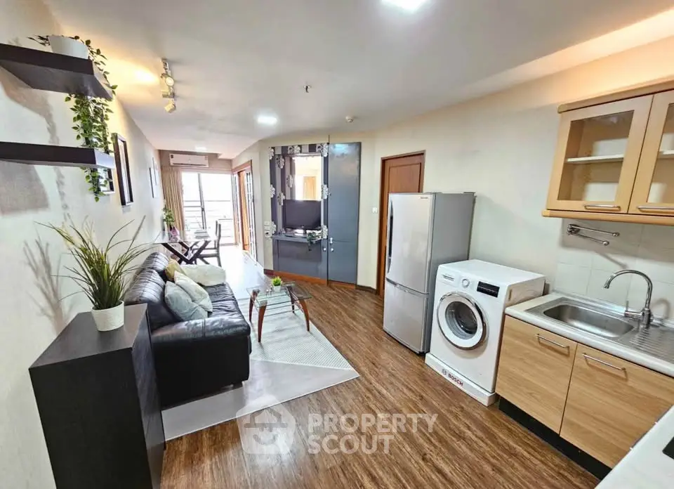 Modern open-layout living room with kitchen, featuring sleek appliances and stylish decor.