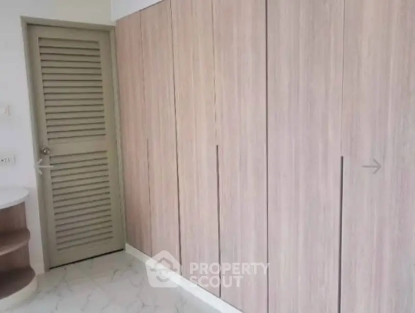 Spacious bedroom with built-in wooden wardrobes and elegant door design.