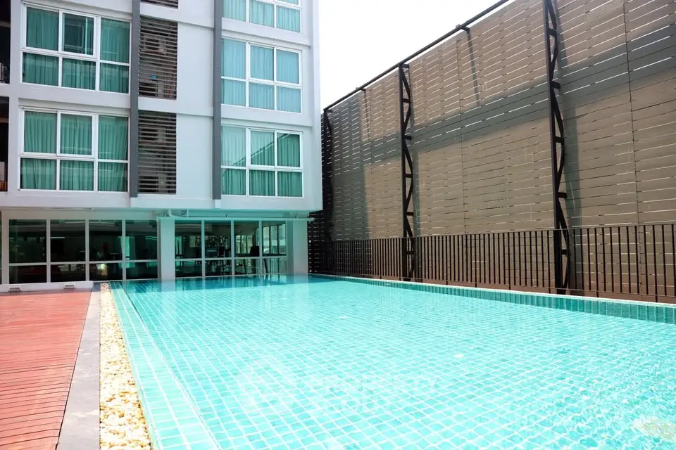 Modern apartment building with a sparkling outdoor pool and stylish deck area.
