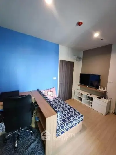 Modern living room with blue accent wall, cozy seating, and entertainment center.