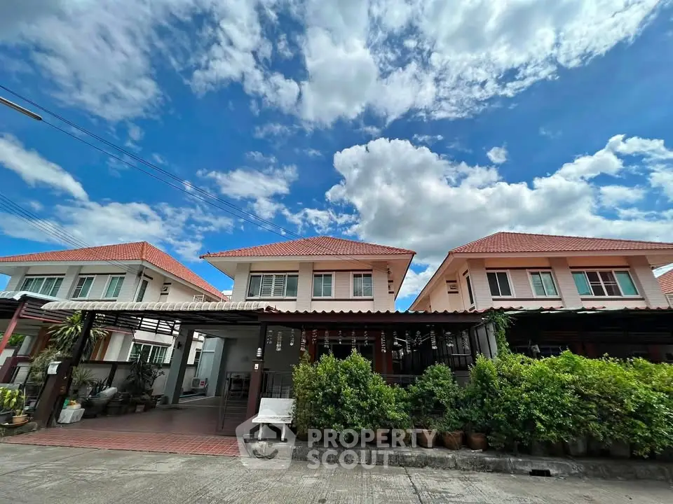 Charming suburban houses with red roofs under a vibrant blue sky, showcasing lush greenery and a welcoming entrance.