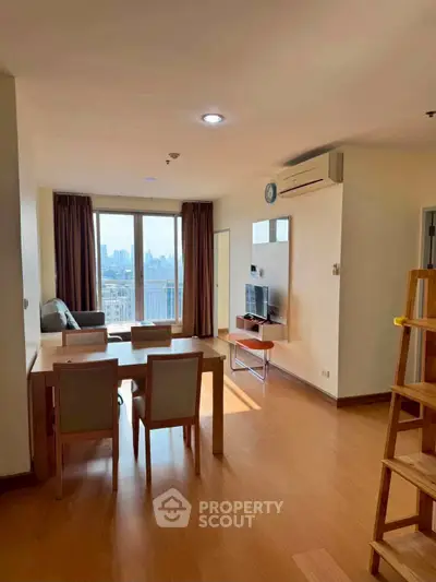 Spacious living room with city view, modern furniture, and natural light in a high-rise apartment.