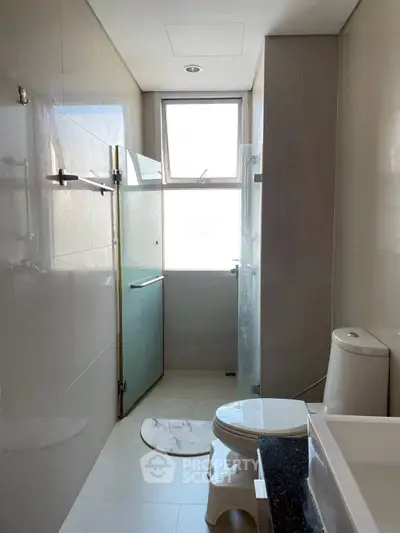 Modern bathroom with glass shower and sleek fixtures in a bright, minimalist design.