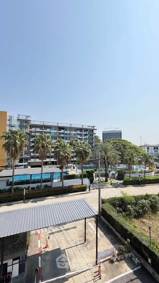 Modern urban building with palm trees and clear blue sky, showcasing vibrant city living.