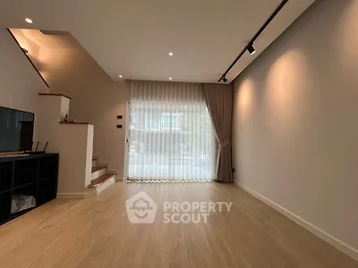 Spacious modern living room with wooden flooring and large window drapes