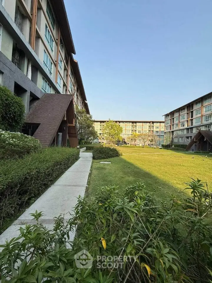 Modern apartment complex with lush green garden and clear blue sky