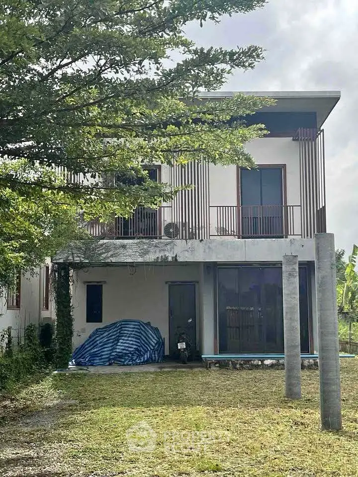 Modern two-story house with large windows and lush greenery