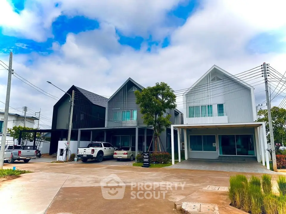 Modern residential houses with sleek design and spacious driveway under a vibrant blue sky.