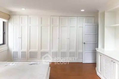 Spacious bedroom with elegant white built-in wardrobes and hardwood flooring