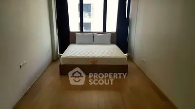 Spacious bedroom with large window and minimalist design, featuring a comfortable bed and wooden flooring.