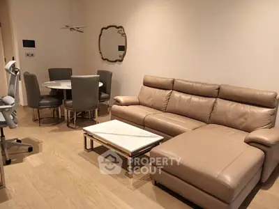 Modern living room with leather sofa and dining area, featuring elegant decor and wooden flooring.