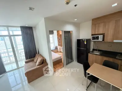 Modern apartment interior with open kitchen and cozy living area, featuring city view balcony.