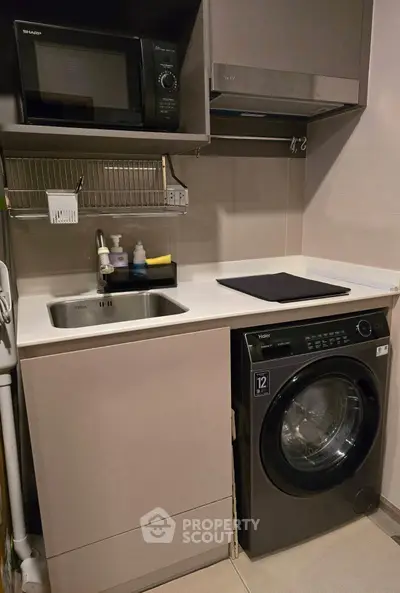 Compact kitchen with modern appliances including washing machine and microwave.