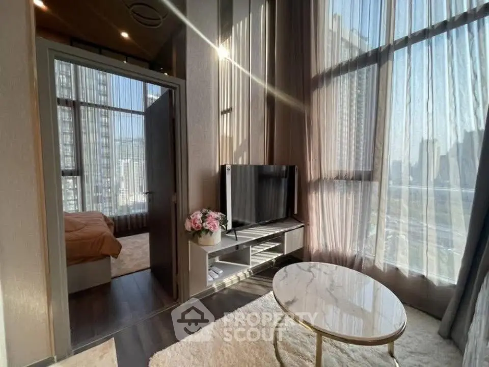 Modern living room with high ceilings and large windows offering city views.
