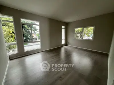 Spacious empty room with large windows and hardwood floors, perfect for customization.