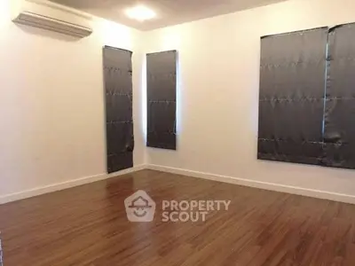 Spacious empty room with wooden flooring and air conditioning, perfect for customization.