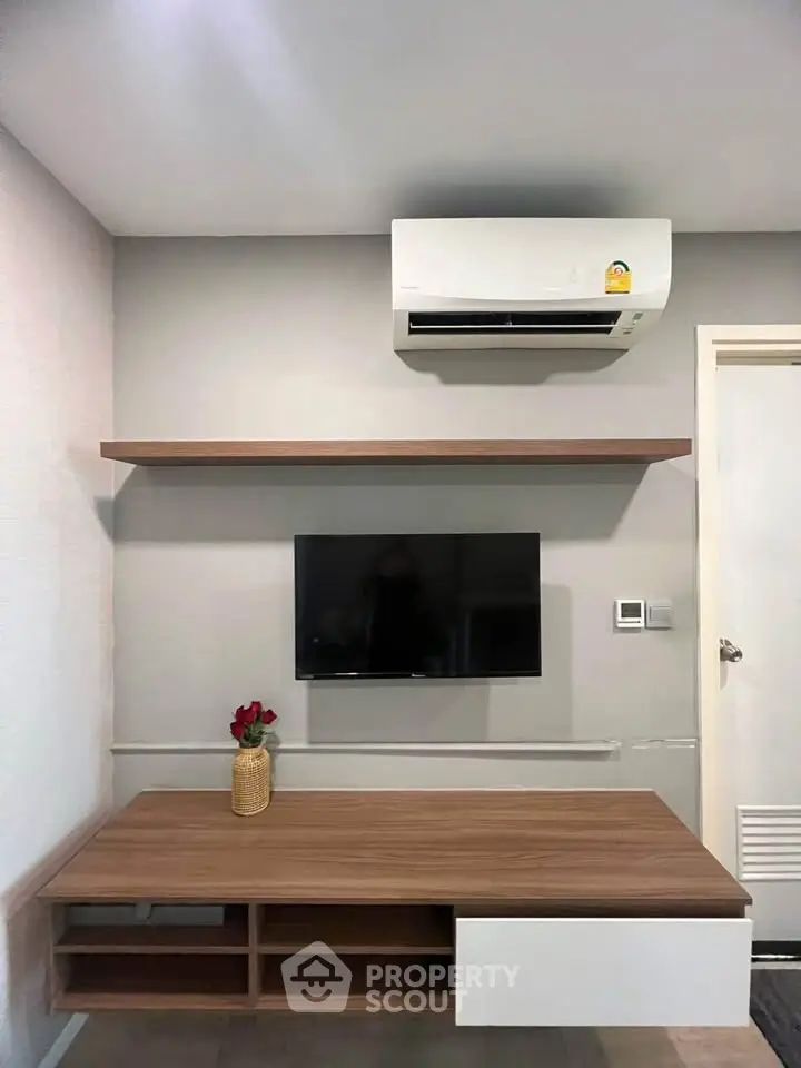 Modern living room with sleek TV setup and air conditioning unit.
