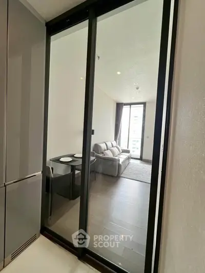 Modern apartment with glass sliding door leading to cozy living room and dining area.